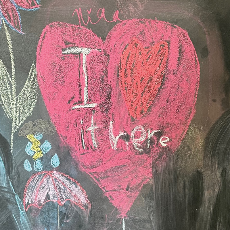 a childs chalk drawing of a heart with the words i love it here.